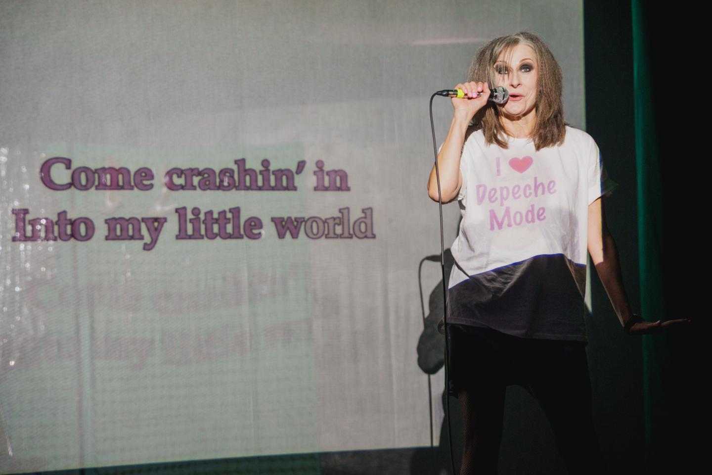 Aktorka pokazana z mikrofonem w prawej dłoni. Śpiewa karaoke. 