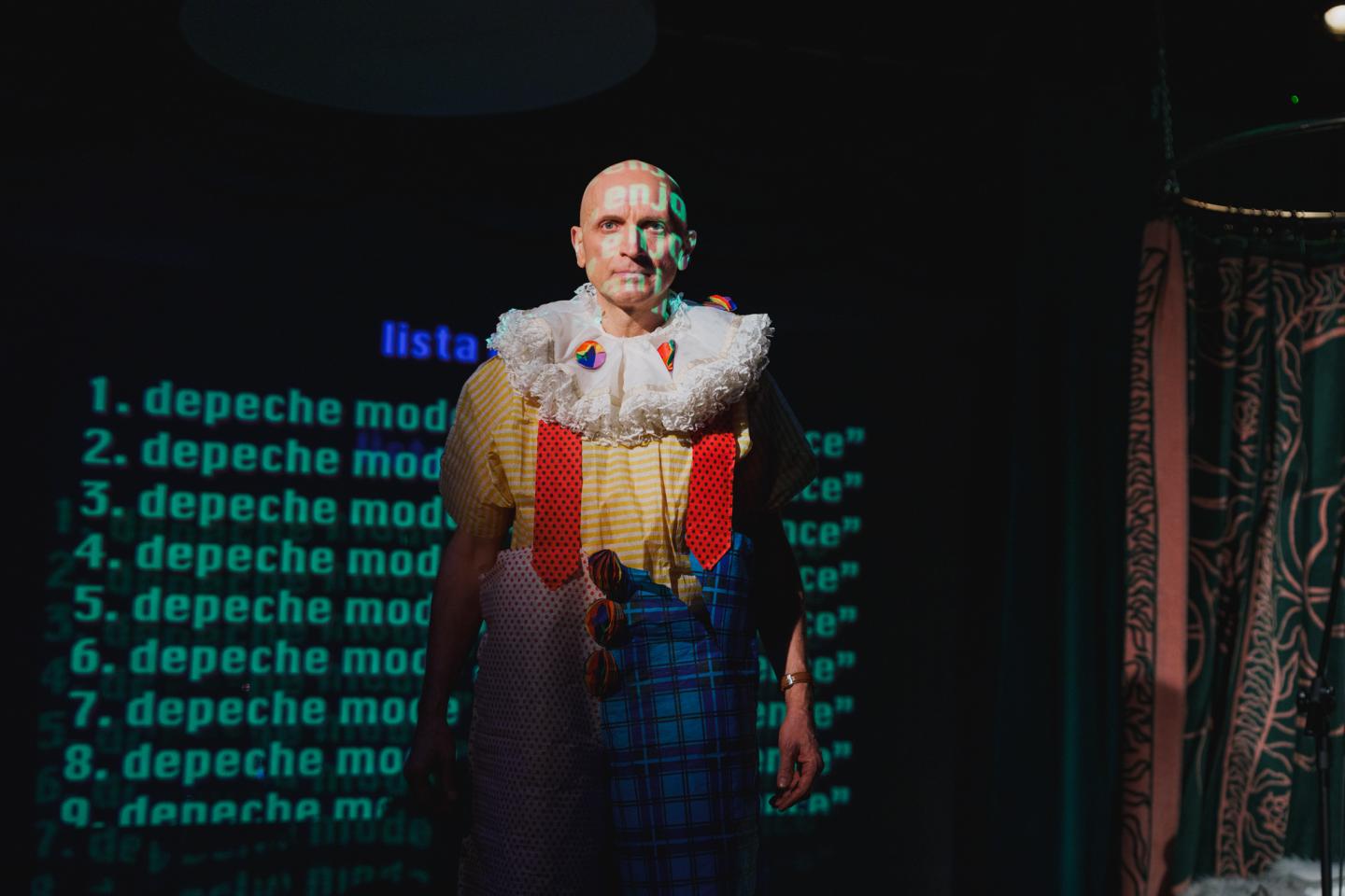 Aktor ubrany w kolorowy strój klauna. 